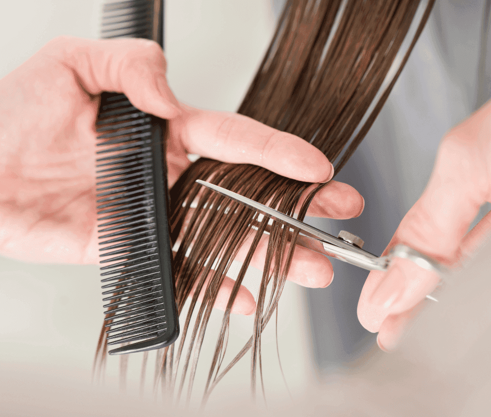 Hairdresser trimming brown hair with scissors and comb.